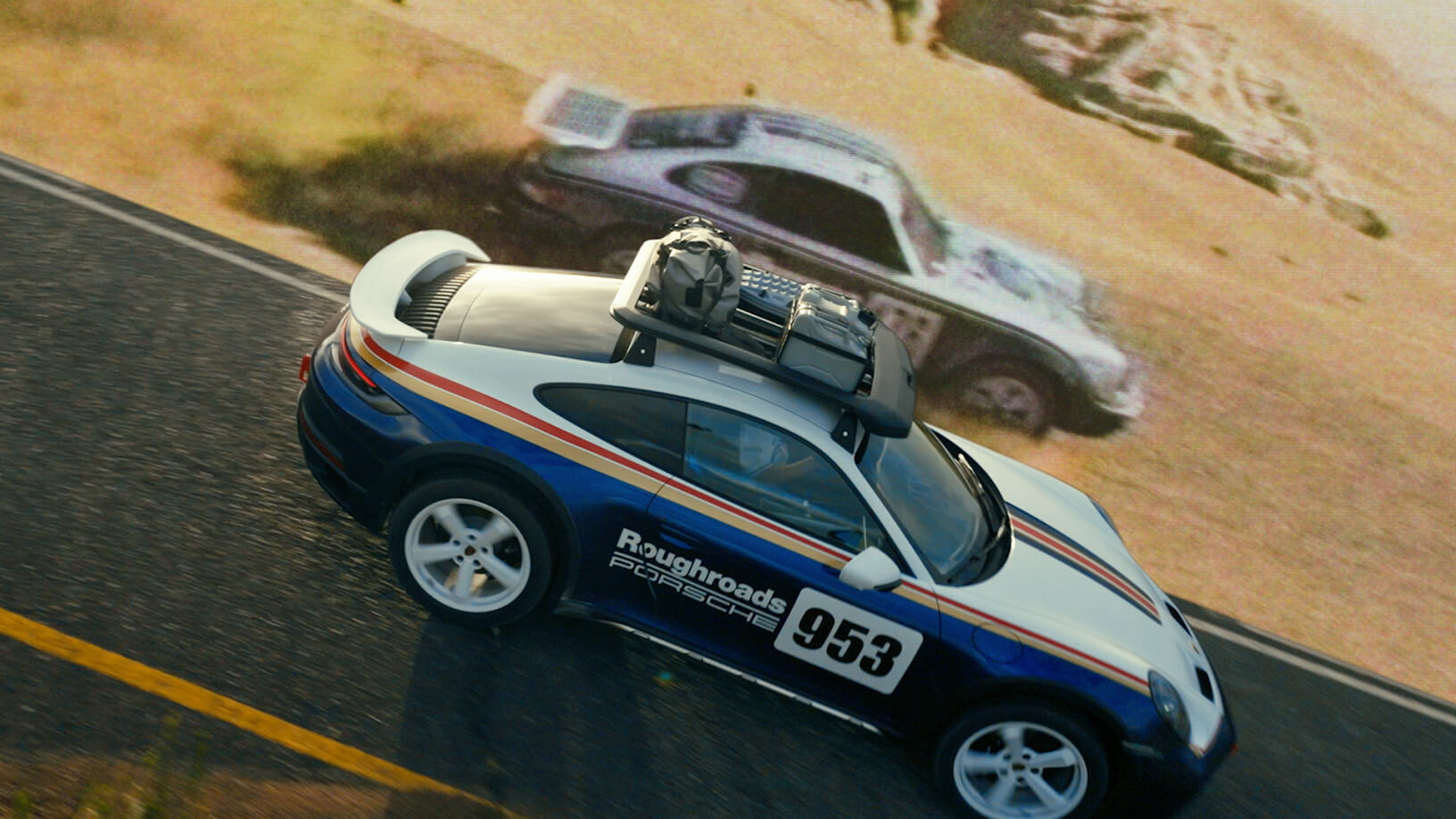 Classic and modern Porsche rally cars race together along a desert road.
